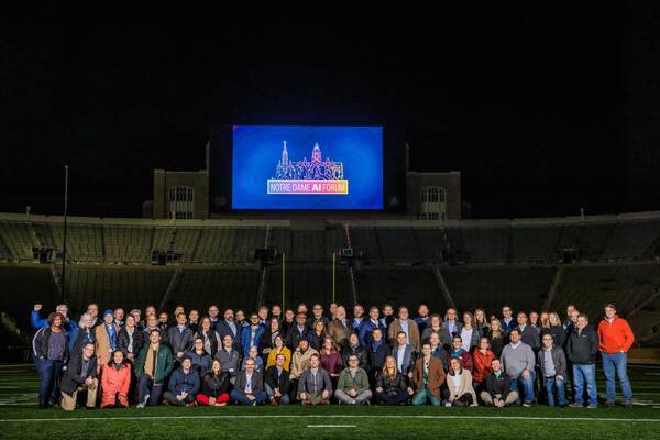 Participants at the Notre Dame AI Forum 2023 pose for a photo on the field of Notre Dame Stadium.